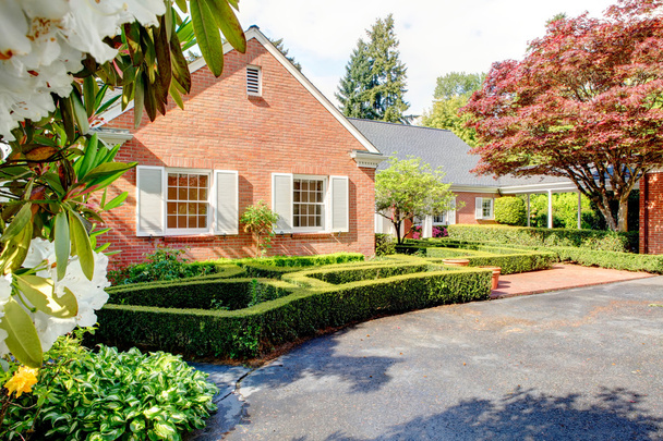 Brick red house with English garden and white window shutters. - Photo, Image