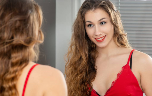 a young smiling woman putting makeup in the mirror - Photo, Image