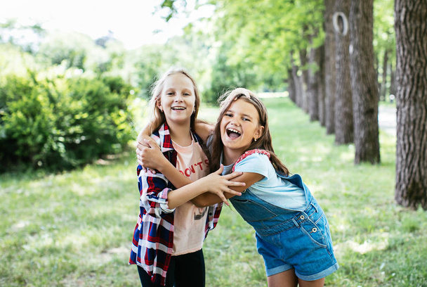 teen girls walk, laugh and play in a green park for a break, positive schoolgirl girlfriend - Φωτογραφία, εικόνα