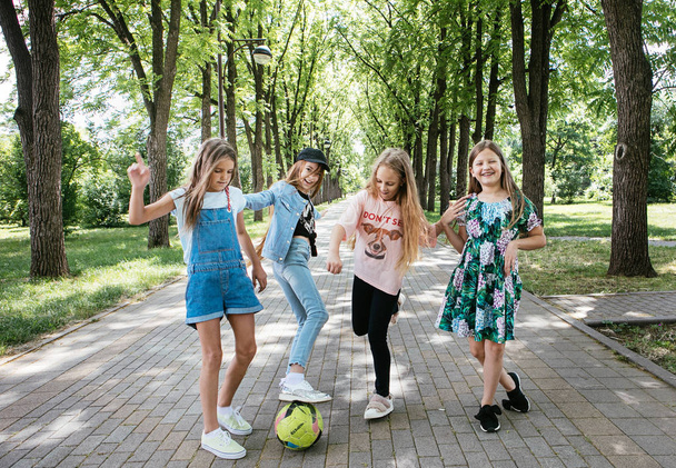 vier tiener meisjes lopen, lachen en spelen in een groen park voor een vakantie, positieve schoolmeisje vriendin - Foto, afbeelding