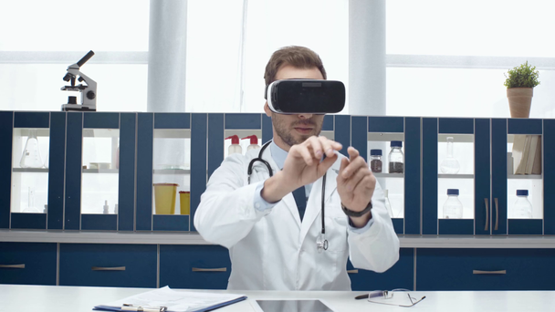 αρσενικό ο γιατρός σε λευκό τρίχωμα φοράει ακουστικό vr και βιώνει την εικονική πραγματικότητα στην κλινική - Πλάνα, βίντεο