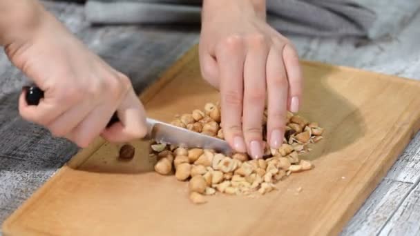 Female chefs hands chopping hazelnuts on wooden cutting board. - Footage, Video