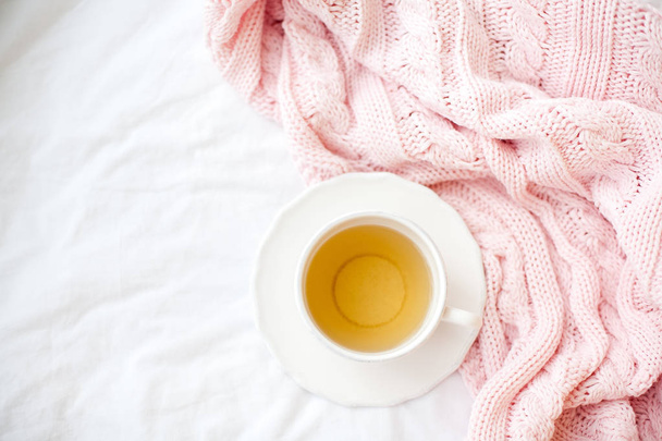 Belle tasse blanche avec thé sur le lit, plaid tricoté rose. Petit déjeuner au lit. Bonjour. Printemps
. - Photo, image