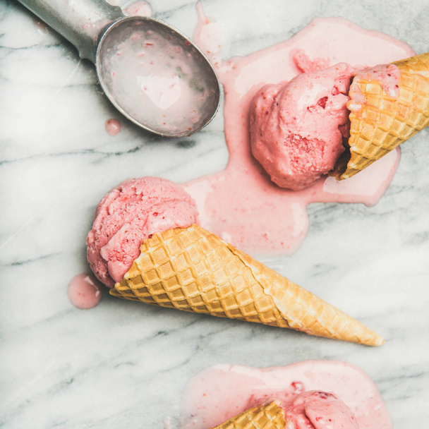 Healthy low calorie summer dessert. Homemade strawberry yogurt ice cream in sweet waffle cones on over grey marble table background, top view, close-up. Clean eating, dieting food concept - Photo, image