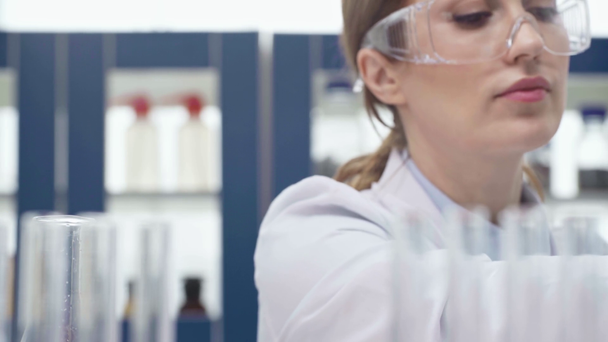 vrouwelijke wetenschapper in bril kolf met rode vloeistof te houden tijdens het experiment in laboratorium - Video