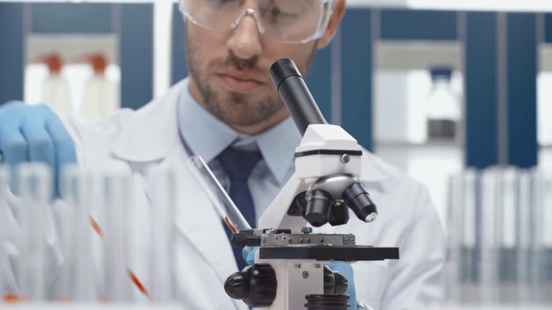 мужчина-ученый в очках, просматривающий микроскоп в лаборатории
 - Кадры, видео