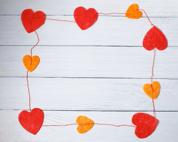 Ημέρα του Αγίου Βαλεντίνου αγάπη έννοια: ορθογώνιο πλαίσιο της κόκκινο και πορτοκαλί γ καρδιές σε λευκό φόντο ξύλου. Το top view - Φωτογραφία, εικόνα