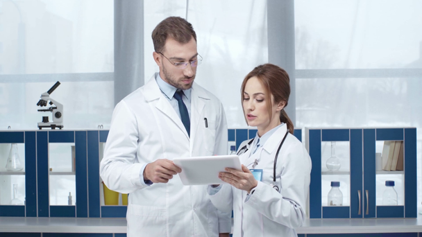 врачи женского и мужского пола в белых халатах с помощью цифрового планшета в клинике
  - Кадры, видео
