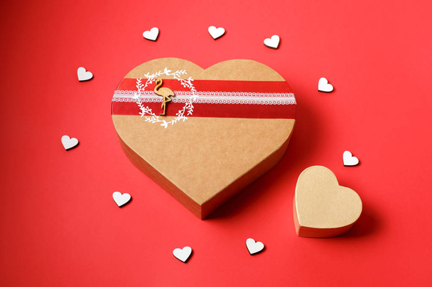 herzförmige Geschenkschachtel auf rotem Hintergrund. Ansicht von oben. fröhlicher Valentinstag. - Foto, Bild
