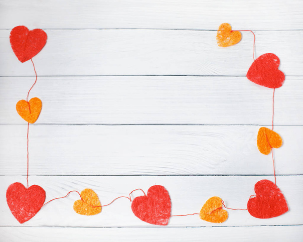 Concepto de amor de San Valentín: Marco rectangular de corazones c rojos y naranjas sobre fondo de madera blanca. Vista superior
 - Foto, imagen