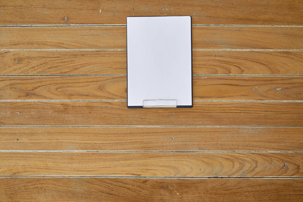 Black clipboard with blank white paper on wooden surface, with plenty of copy space. - Foto, immagini