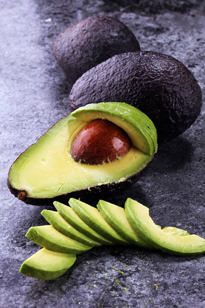 Avocado on old table. Halfs of fresh ripe hass avocado. Fruits healthy food concept - Photo, Image