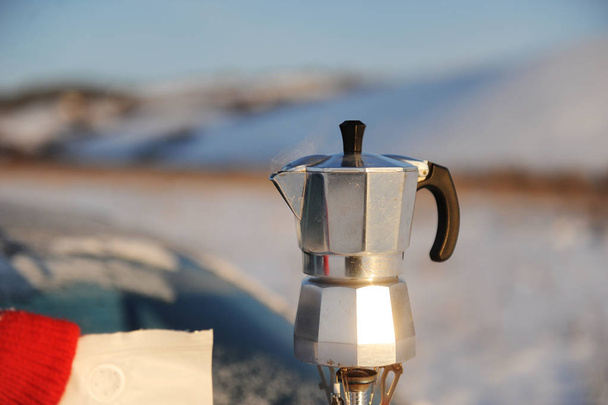 Koffie brouwen in moka pot op een gasbrander op de auto kofferbak buiten in Russische sneeuw winterlandschap. - Foto, afbeelding