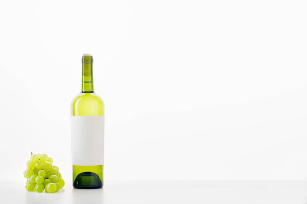 bottle of white wine with bunch of grapes isolated on white background - Foto, Bild