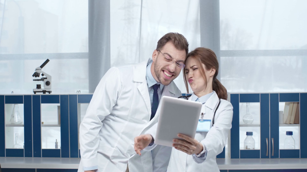 female and male doctors showing various face expressions while taking selfie on digital tablet in clinic  - Footage, Video