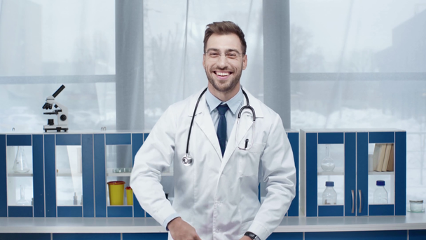 medico maschio in camice bianco guardando la macchina fotografica, sorridendo e gettando soldi in clinica
 - Filmati, video