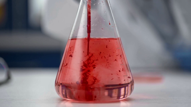 フラスコで赤い液体を攪拌しながら女性化学者のビューをトリミング - 映像、動画