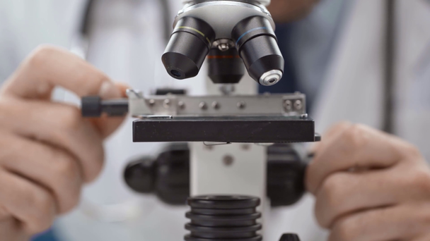 男性の科学者が研究室で顕微鏡を調整するビューをトリミング - 映像、動画