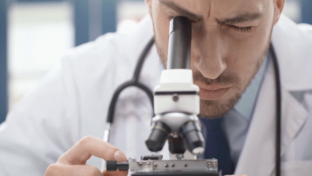 Selektivní fokus mužské vědce dívá skrze mikroskop v laboratoři - Záběry, video