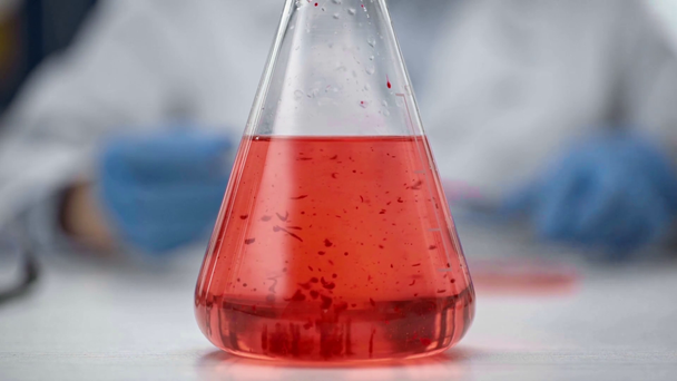 oříznutý pohled na ženské chemik míchání červená kapalina v baňce - Záběry, video