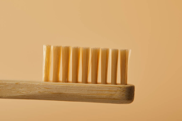 ベージュ色の背景に茶色の竹の歯ブラシのビューをクローズ アップ - 写真・画像