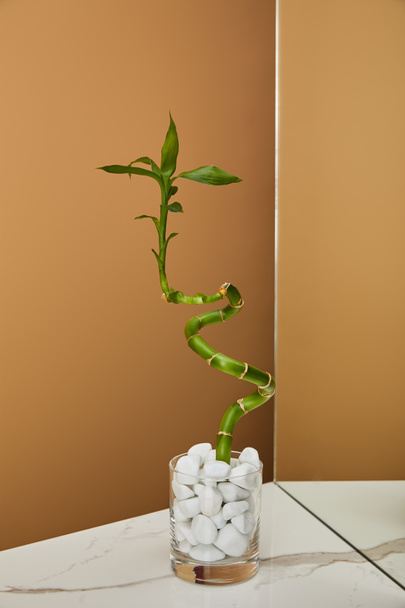 stelo di bambù in vaso con pietre e specchio su tavolo in marmo bianco e fondo beige
 - Foto, immagini