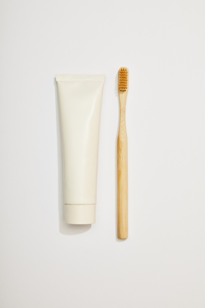top view of bamboo toothpaste in tube and toothbrush on white background - Fotó, kép