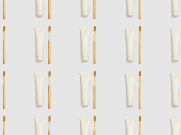 Bambuszahnbürsten und Zahnpasta in Tuben auf grauem Hintergrund, nahtloses Hintergrundmuster - Foto, Bild