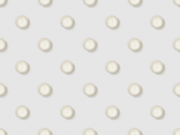 crema cosmética en recipientes sobre fondo gris, patrón de fondo sin costuras
 - Foto, imagen