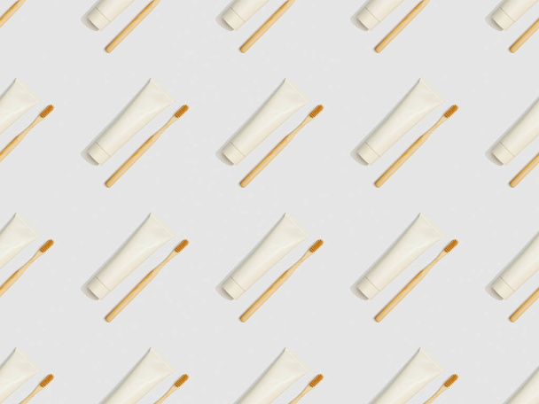 diagonally located toothbrushes and toothpaste in tubes on grey background, seamless background pattern - Photo, image