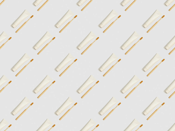 cepillos de dientes de bambú ubicados en diagonal y pasta de dientes en tubos sobre fondo gris, patrón de fondo sin costuras
 - Foto, Imagen