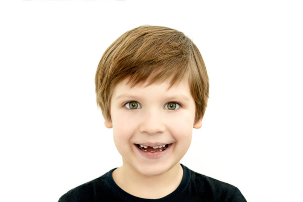 laughing boy without baby tooth, the absence of a baby tooth, a tooth fell out of a child, a toothless smile, a dentist, white teeth of a child, n black t-shirt on white background, the absence of a baby tooth - Photo, Image