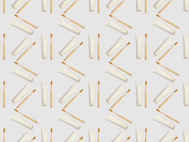 escovas de bambu e pasta de dentes em tubos em diferentes direções sobre fundo cinza, padrão de fundo sem costura
 - Foto, Imagem