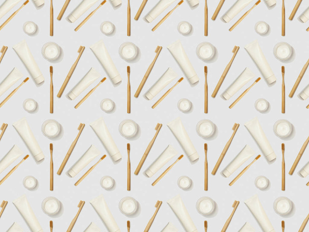 bamboo toothbrushes, toothpaste in tube in different directions and cosmetic cream on grey background, seamless background pattern - Photo, image
