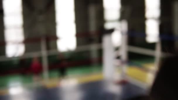 Portait of sportsman punching in black boxing gloves and looking seriously at camera in the gym. Close up tired from workout strength. strong body. Slow motion. Boxing ring on the background - Záběry, video