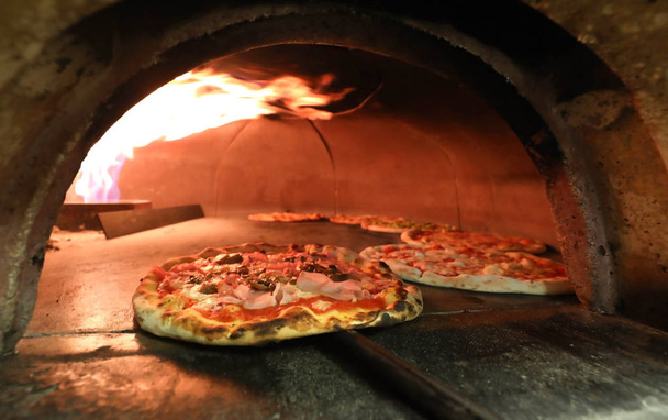 fuego y muchas pizzas dentro de un horno en la pizzería italiana
 - Foto, Imagen