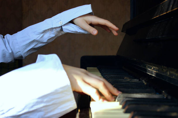 Молодая девушка старательно играет на пианино. Обрезанный кадр маленькой девочки, играющей на пианино. Обрезанный вид на руки пианиста
. - Фото, изображение