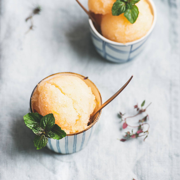 Fresh homemade grapefruit sorbet ice cream scoops in ceramic cups over linen napkin, square crop. Healthy vegan summer dessert - Zdjęcie, obraz