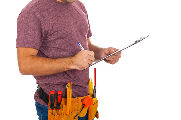 Close up picture of a repairman with toolbelt and holding a clipboard on isolated background - Фото, зображення