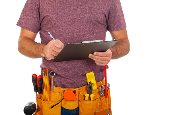 Close up picture of a repairman with toolbelt and holding a clipboard on isolated background - Foto, Imagem