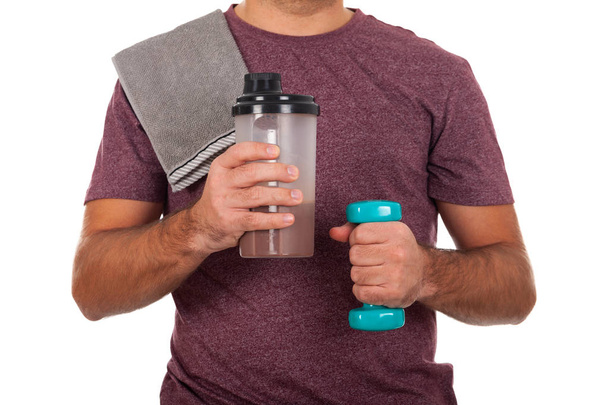 Close up picture of a young man holding a dumbbell and a shake - Zdjęcie, obraz