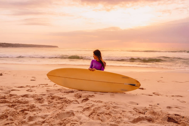 Surfer-Mädchen mit Surfbrett am Strand bei Sonnenuntergang - Foto, Bild