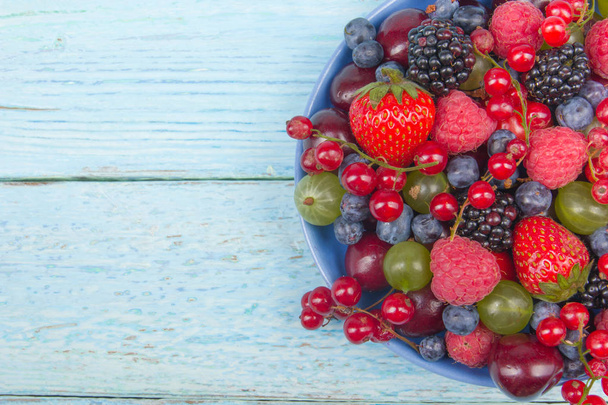 Varias bayas frescas de verano en un tazón sobre una mesa de madera rústica. Antioxidantes, dieta de desintoxicación, frutas orgánicas
 - Foto, Imagen