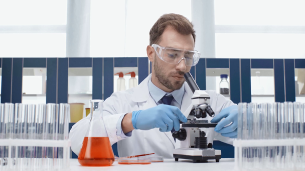 férfi tudós használ Mikroszkóp alatt vérvizsgálatot laboratóriumi védőszemüveget - Felvétel, videó