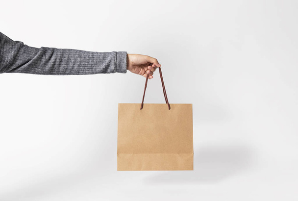 Hand holding blank brown paper bag for mockup template advertising and branding on gray background.  - Fotografie, Obrázek