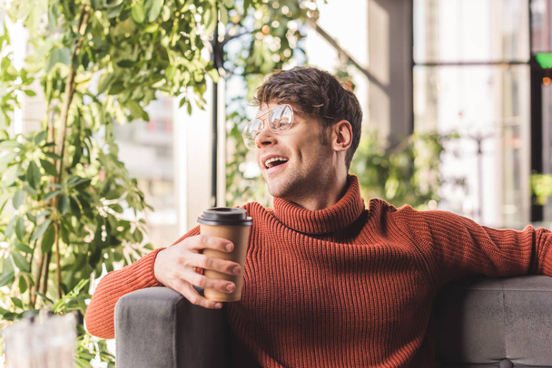 cheerful man in glasses holding paper cup in cafe - Foto, imagen
