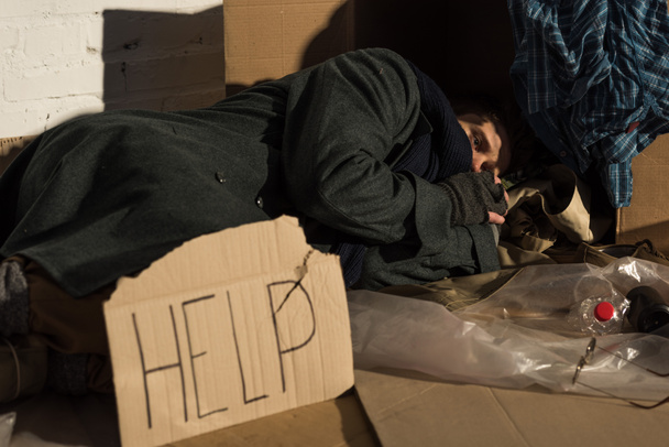 ゴミ捨て場のダン ボールの上に横たわるホームレスの男性を落ち込んでください。 - 写真・画像