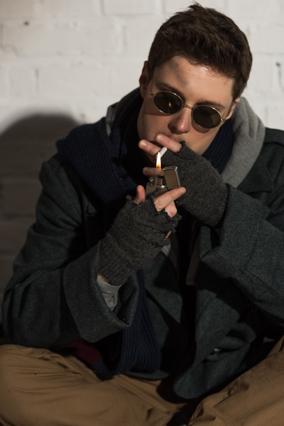 homeless man in fingerless gloves lighting cigarette - Photo, Image