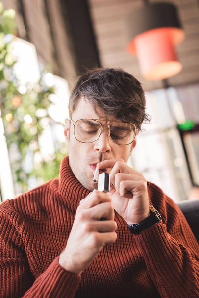 handsome man in glasses smoking cigarette in cafe - Photo, Image
