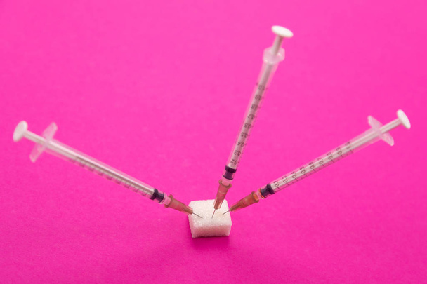 белые медицинские шприцы торчат из куска сахара
 - Фото, изображение